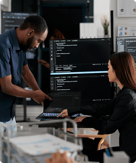 Engineers reviewing code on multiple monitors